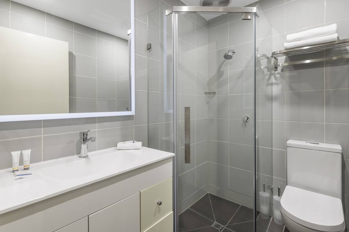 Une salle de bain moderne avec une douche à parois de verre, un lavabo blanc et des toilettes.