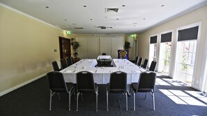 A conference room with a long table, black chairs, and a flag. - Quality Hotel Melbourne Airport (Westmeadows)