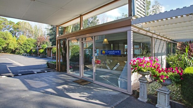 A Comfort Inn hotel entrance with a covered walkway, glass doors, and potted plants. - Moe Parklands Motel (Newborough)