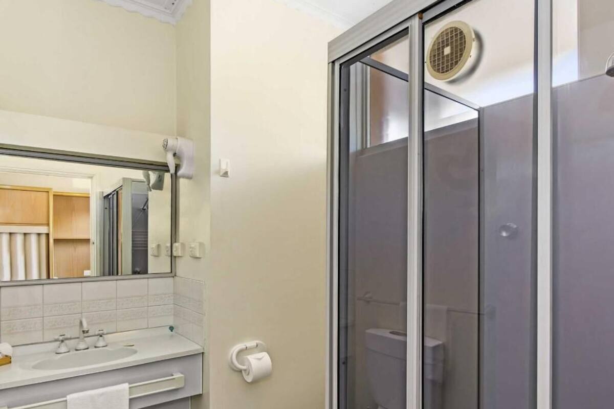 Ein Badezimmer mit einer Duschkabine, einem Waschbecken mit Handtuch und einer Toilette.