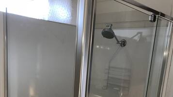 A glass-enclosed shower area with a handheld showerhead.