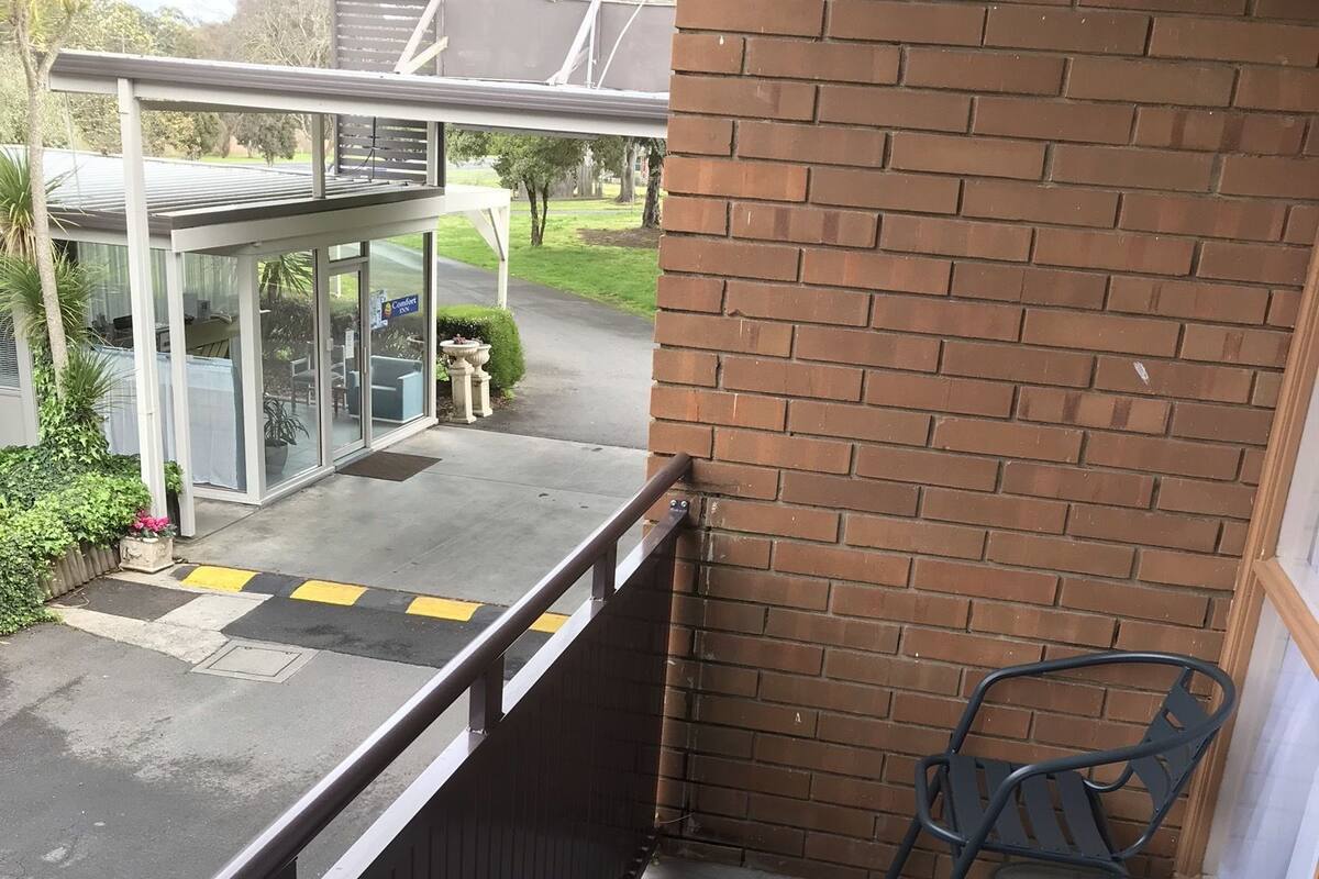 Ein Balkon mit einer Ziegelwand, einem Metallgeländer und zwei Metallstühlen.