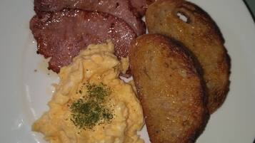 A plate with sliced ham, fried potatoes, and macaroni salad.