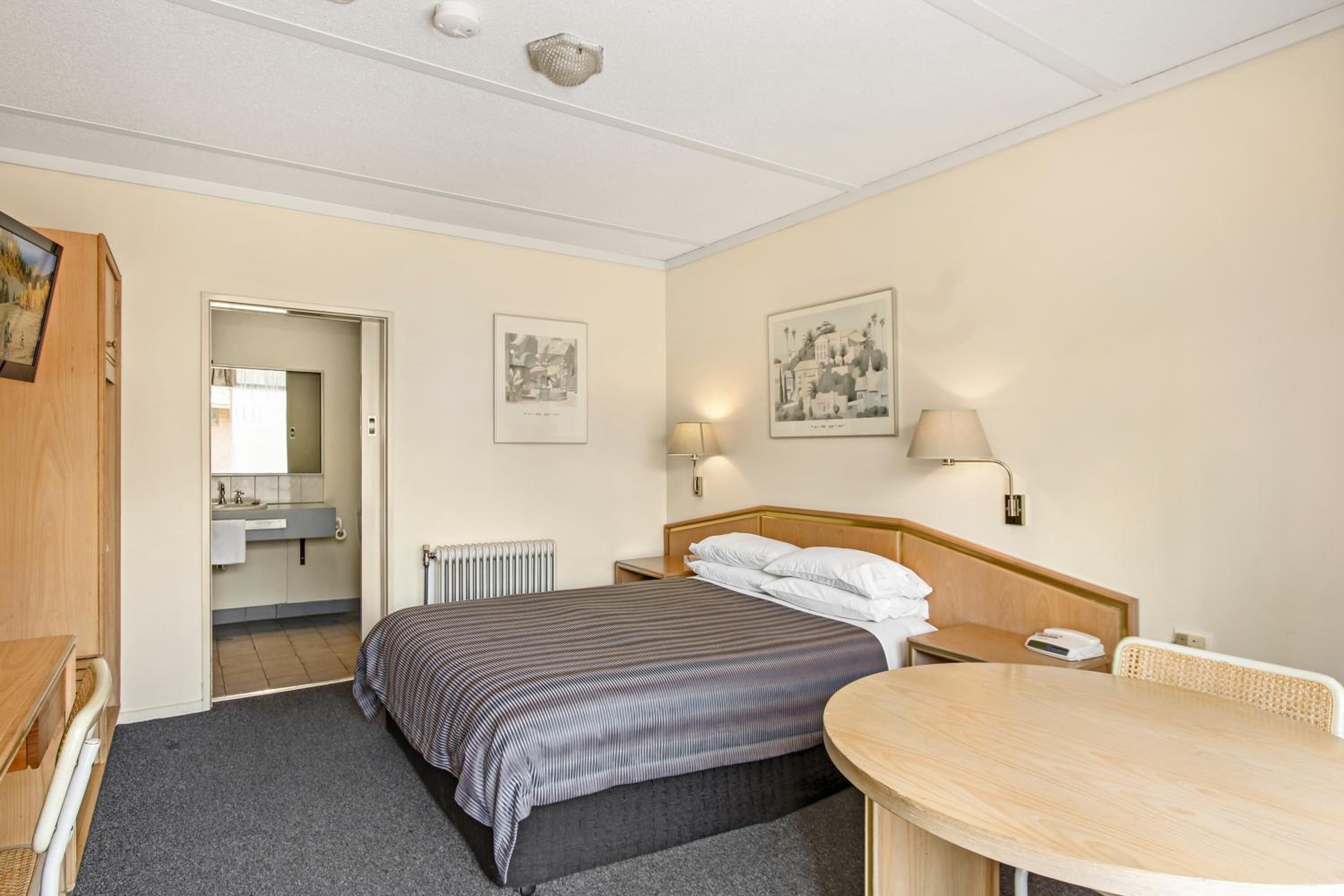 Ein Hotelzimmer mit Bett, Nachttisch, Lampe und einem kleinen Tisch.