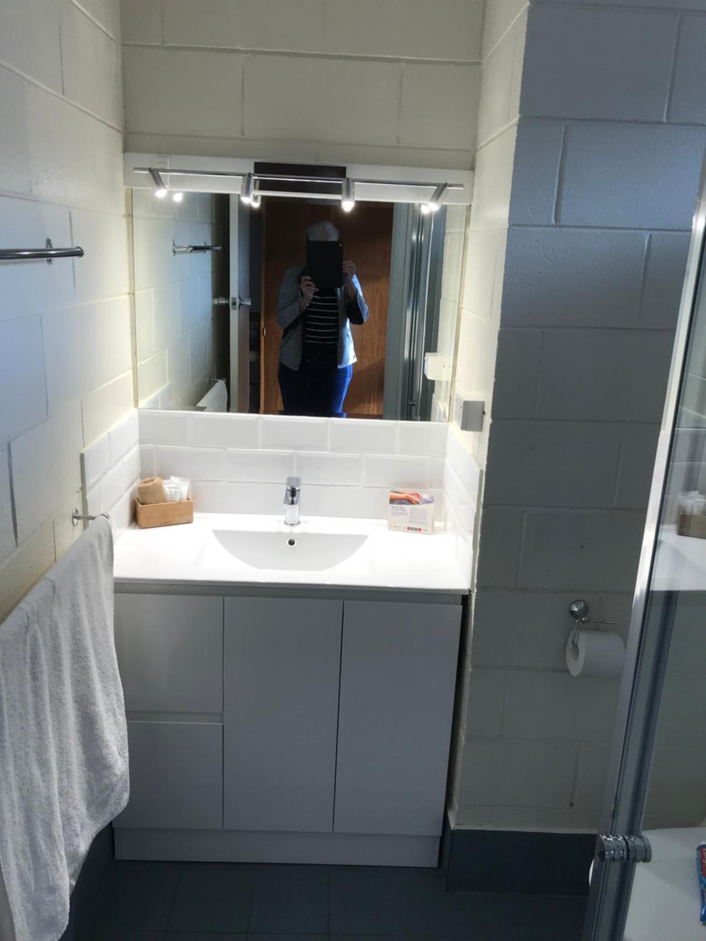 Une salle de bain avec un lavabo blanc, un miroir et un porte-serviettes.
