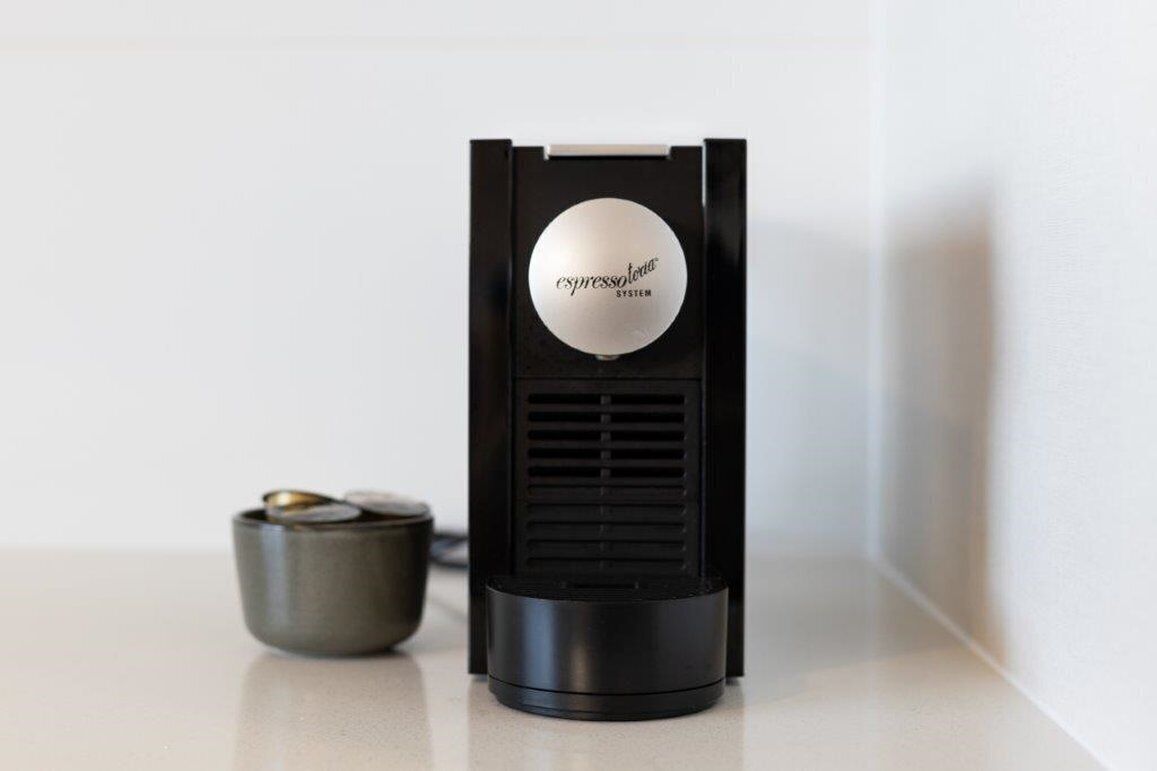 A coffee machine with a circular display on top, placed on a countertop next to a small bowl.