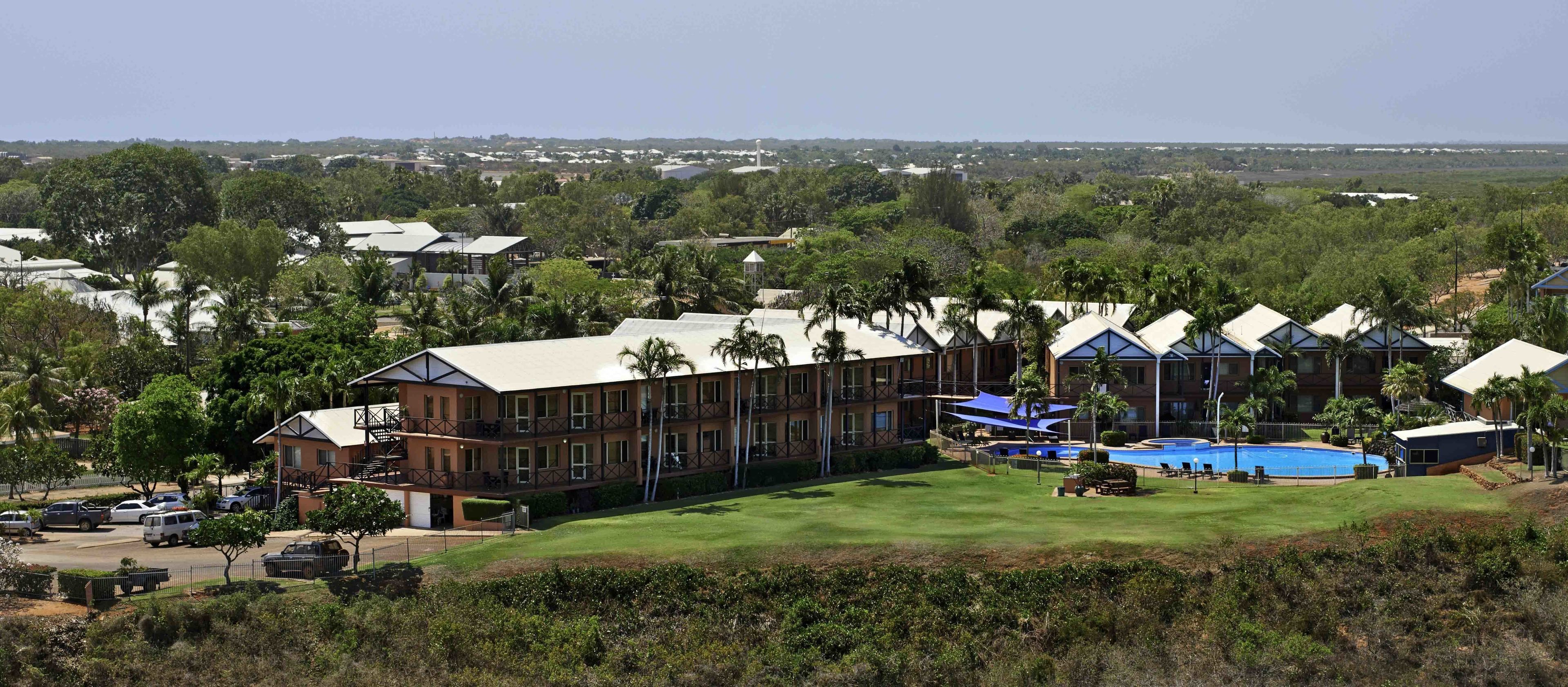 A resort with multiple buildings, a swimming pool, and a well-maintained lawn.