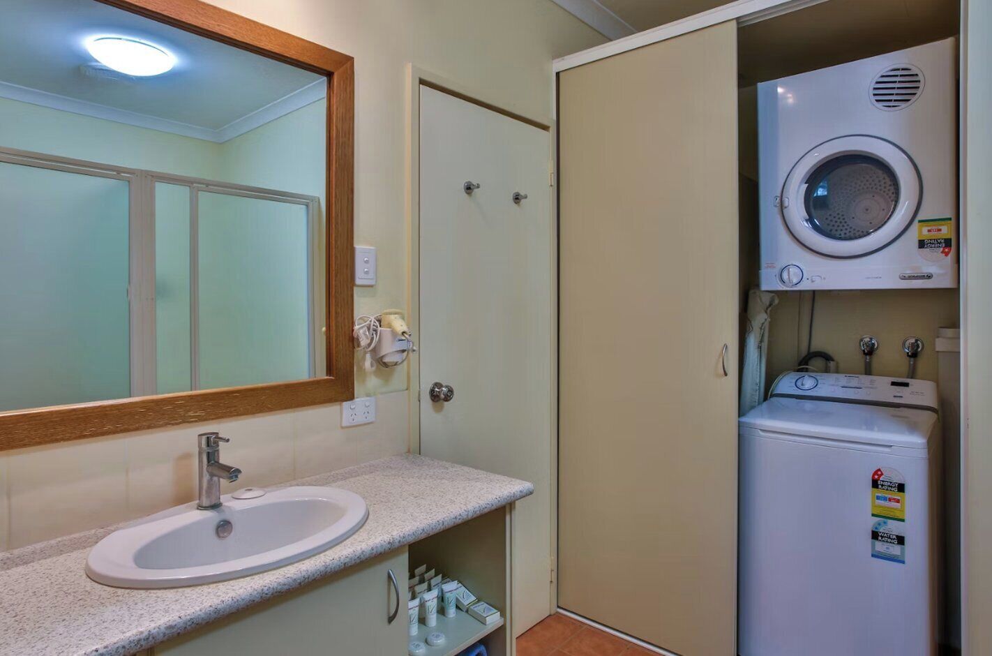 A compact bathroom with a sink, mirror, and a washing machine.