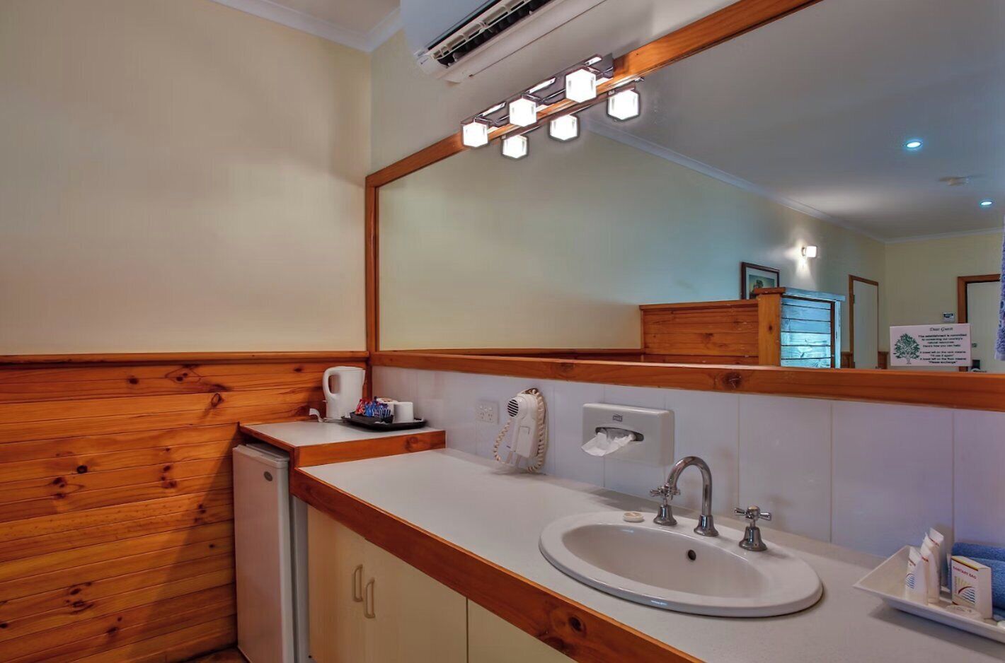 A bathroom with a wooden vanity, a sink, a mirror, and a towel rack.