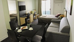 A hotel room with a dining table, chairs, a sofa, a bed, a television, and a balcony with a view. - Comfort Inn & Suites Goodearth Perth (Perth)