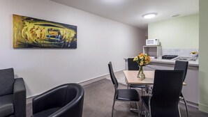A modern kitchen with a microwave, sink, and a dining area with chairs and a table. - Comfort Inn & Suites Goodearth Perth (Perth)