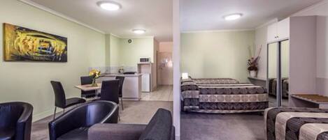 A compact hotel room with a bed, a desk, a chair, and a sofa.
