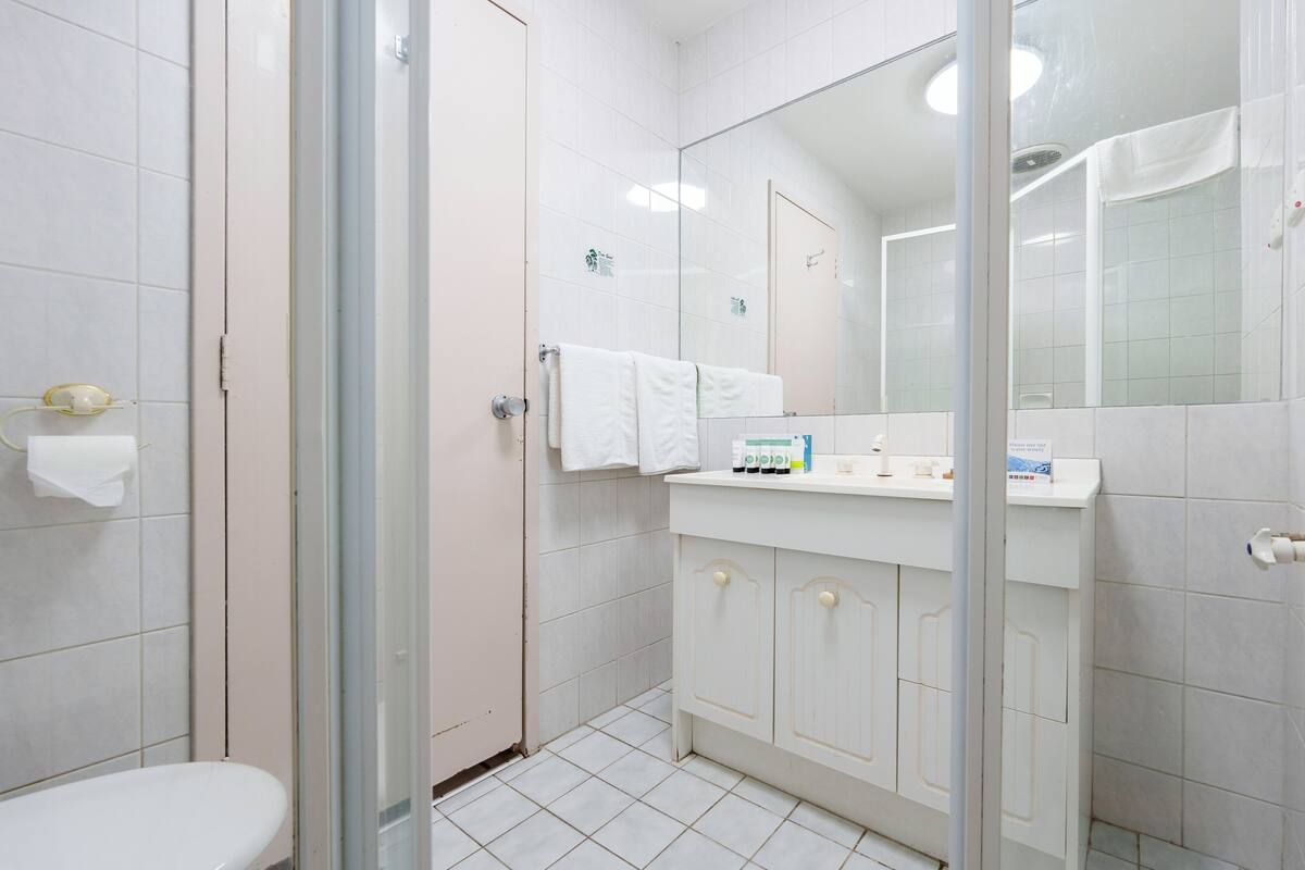Un baño con cabina de ducha de vidrio, inodoro blanco y tocador con espejo.