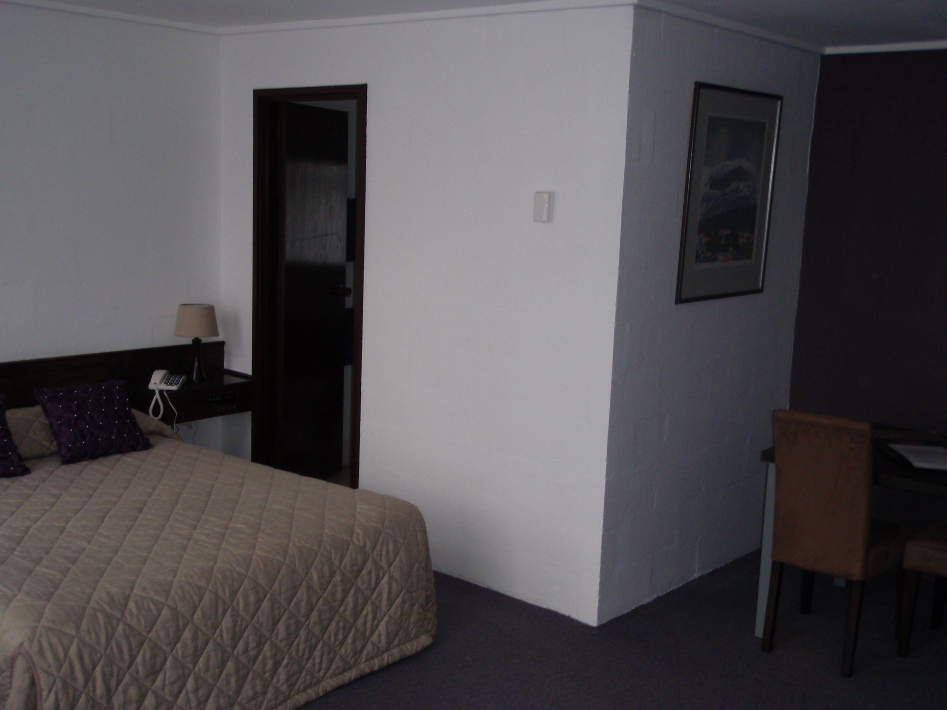 A hotel room with a bed, a desk, and a chair.