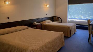 A hotel room with two beds, a chair, a small table with a phone, and a window with a view.