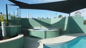 Una piscina con jacuzzi y zona de estar techada.