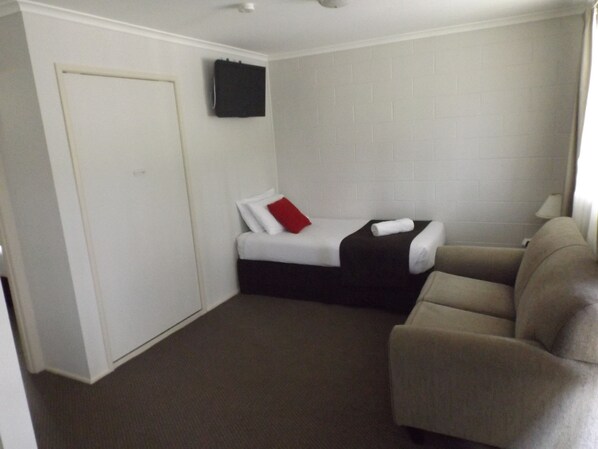 A small, compact room with a single bed, a sofa, and a door.