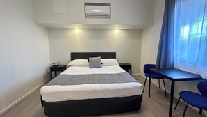 Una habitación de hotel con cama, mesitas de noche, escritorio y sillas.