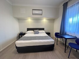 Una habitación de hotel con cama, mesitas de noche, escritorio y sillas.