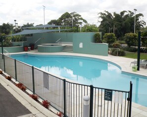 Una piscina al aire libre, sillones reclinables de piscina