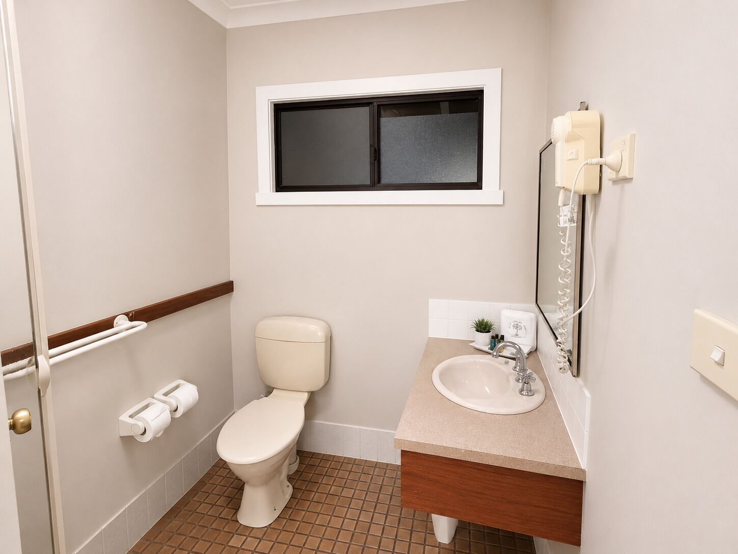 Un baño con inodoro, lavamanos, espejo y ventana.