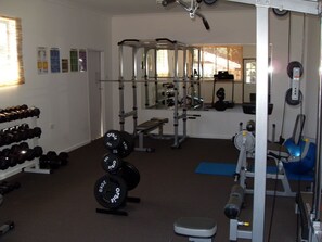 Work out in comfort with a fully equipped gym featuring a squat rack, bench press, cable machine, dumbbells, and weight plates.