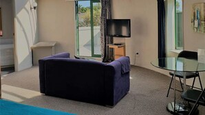 Una habitación moderna con techo curvo, un ventanal grande, un televisor de pantalla plana, un sofá y una mesa de vidrio.