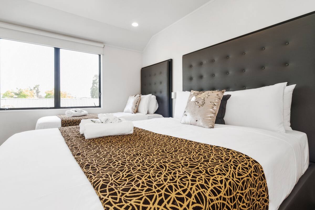 A hotel room with a large bed, a smaller bed, a window, and a dark headboard.