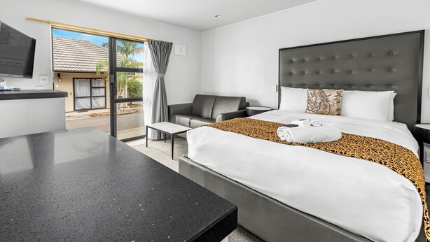 Ein modernes Hotelzimmer mit einem großen Bett, einem Schreibtisch, einem Sessel und einem Fernseher.