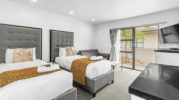 A hotel room with two beds, a TV, and a sliding glass door to the outside.