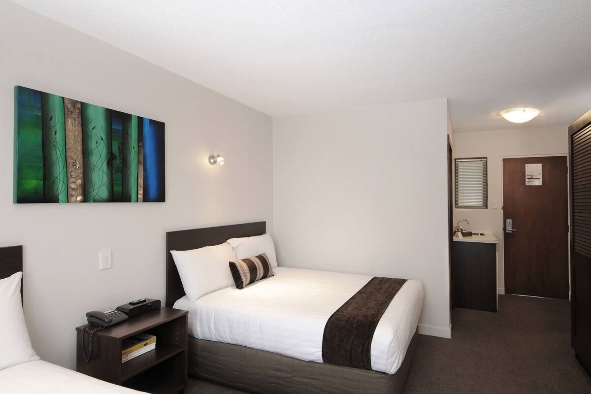 Quarto de hotel com cama, mesa de cabeceira e um quadro na parede.