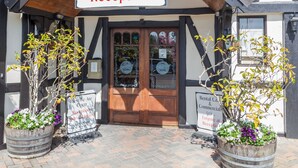 A reception area with a sign above the door, two potted plants, and a tiled roof. - The Surrey Hotel (Auckland)