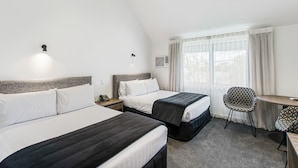 A hotel room with two beds, a desk, a chair, and a window with curtains. - The Surrey Hotel (Auckland)