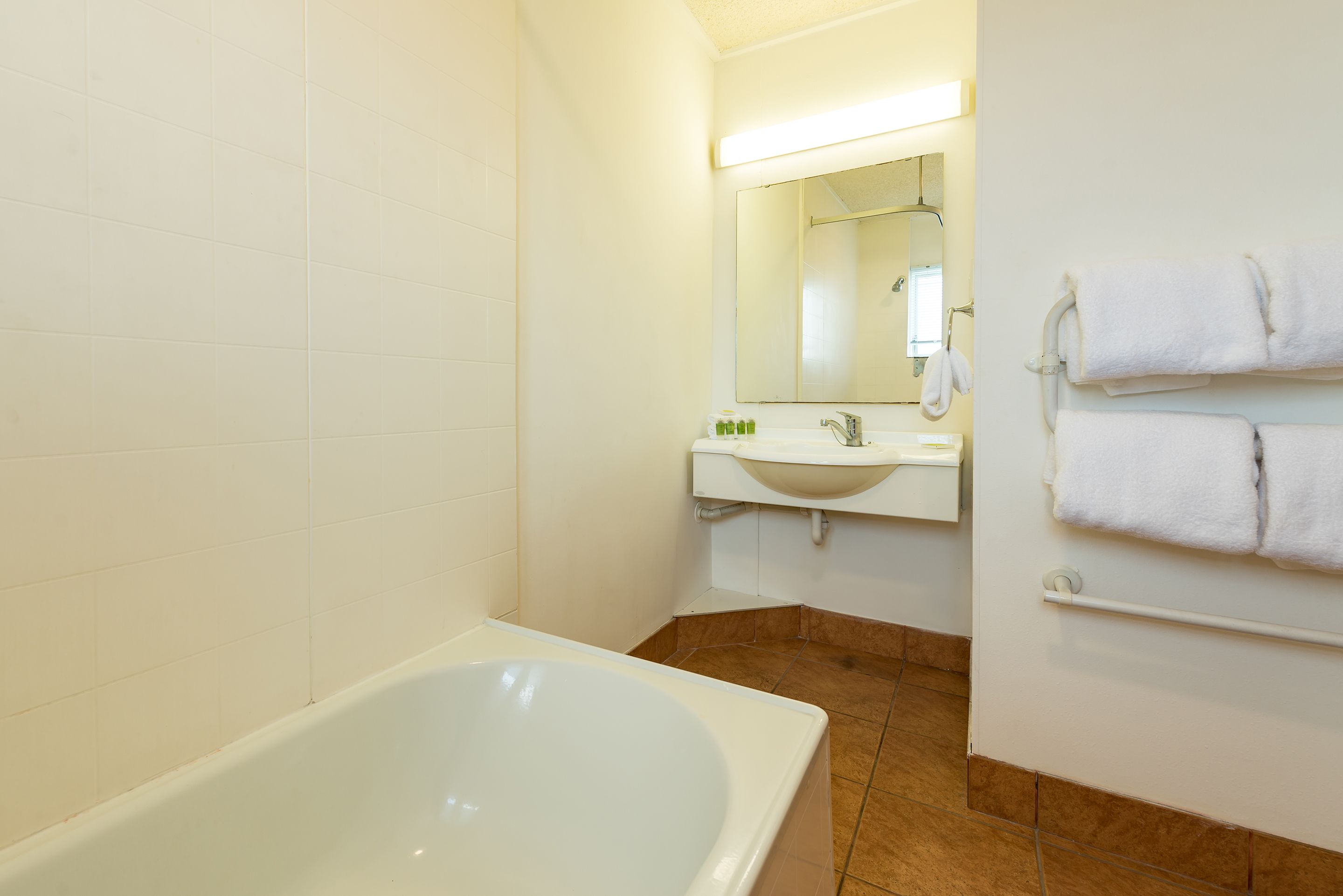 Une salle de bain avec une baignoire, un lavabo et un miroir.