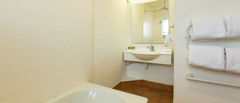 A bathroom with a bathtub, a sink, and a mirror.