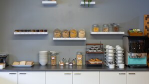 A breakfast bar with various food items, coffee machines, and storage shelves. - Heartland Ambassador Hotel Hamilton (Hamilton)
