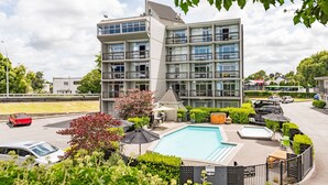 A modern building with multiple balconies and a swimming pool. - Heartland Ambassador Hotel Hamilton (Hamilton)