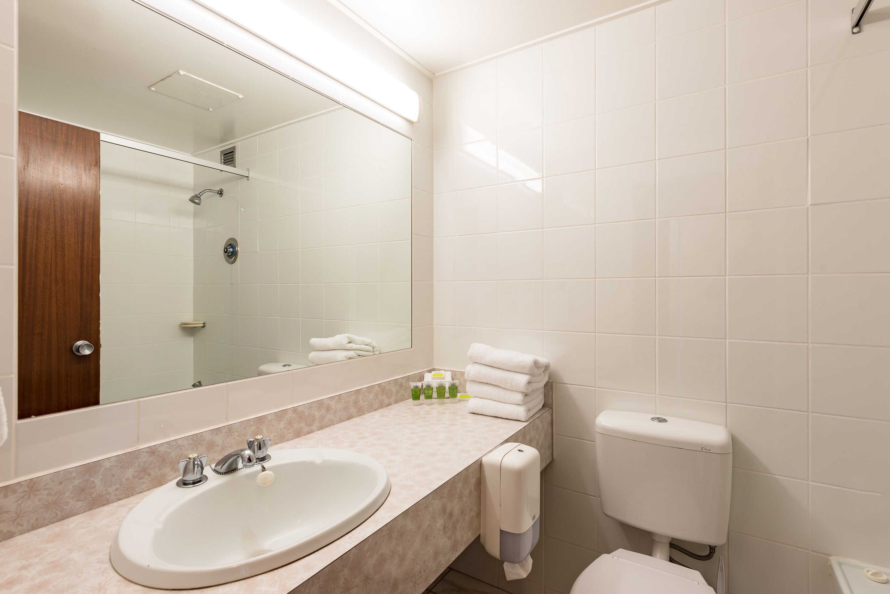 A bathroom with a sink, mirror, toilet, and a towel rack.
