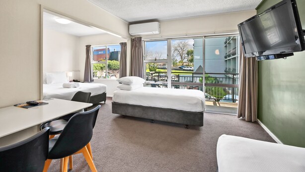 A hotel room with a bed, a desk, chairs, a TV, and a large window with a view of the outside. - Heartland Ambassador Hotel Hamilton (Hamilton)