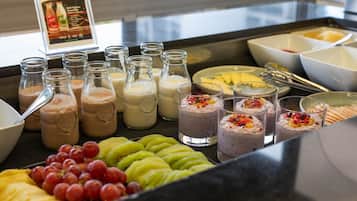 Ein Buffet mit verschiedenen Speisen und Getränken, darunter Früchte, Smoothies und Joghurt-Schüsseln.