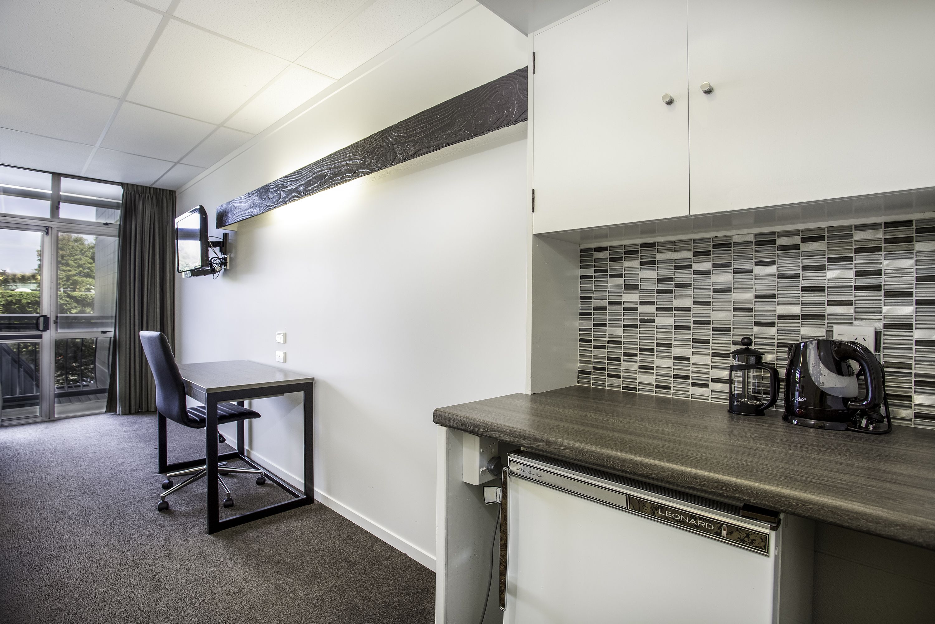 A modern kitchen with a microwave, kettle, and coffee maker on the counter.