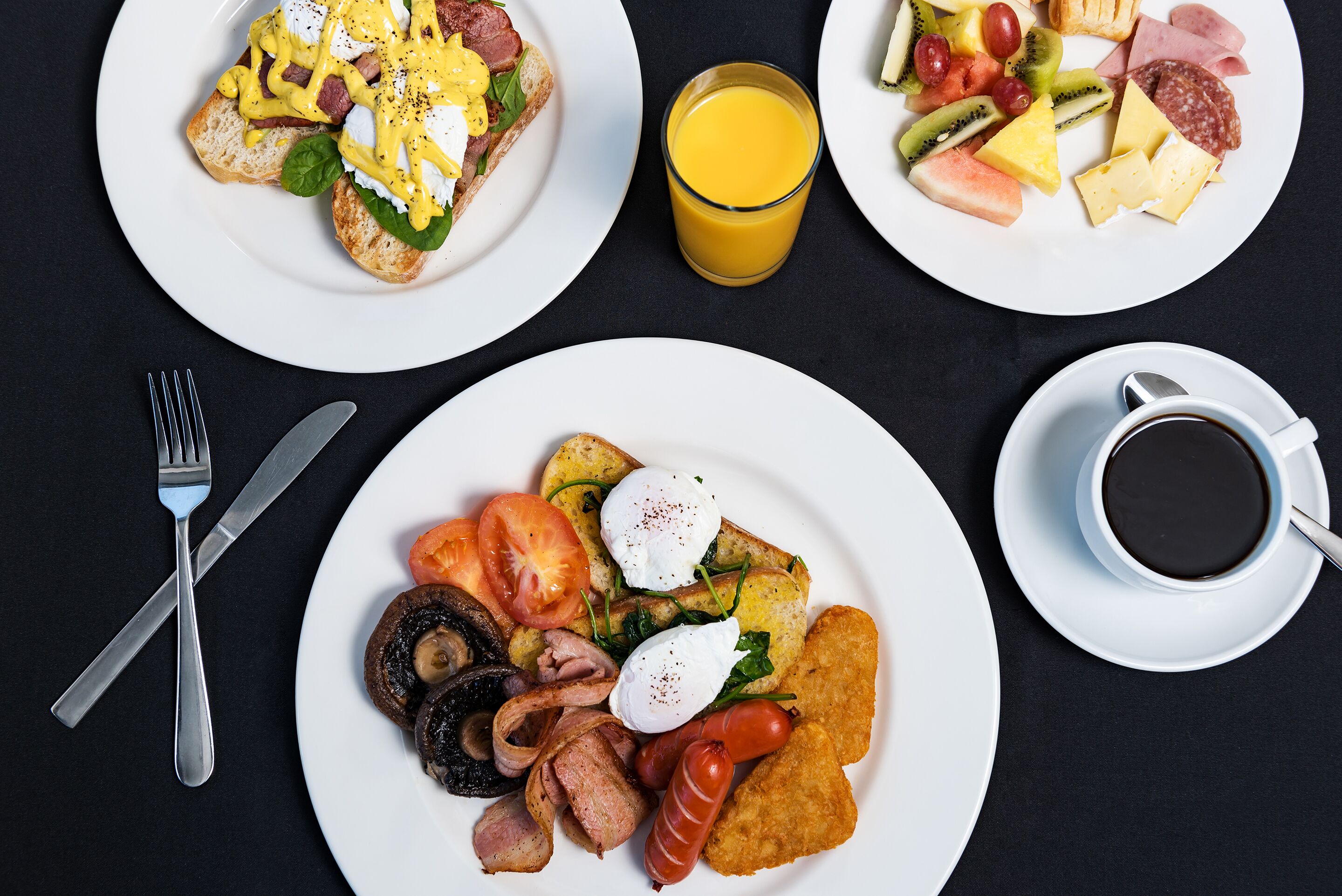 Desayuno con platos de comida, un vaso de jugo de naranja y una taza de café.