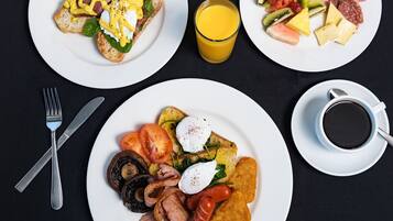 Desayuno con platos de comida, un vaso de jugo de naranja y una taza de café.