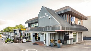 A modern building with a prominent 'The Ambassador' sign, a cafe, and a restaurant. - Heartland Ambassador Hotel Hamilton (Hamilton)