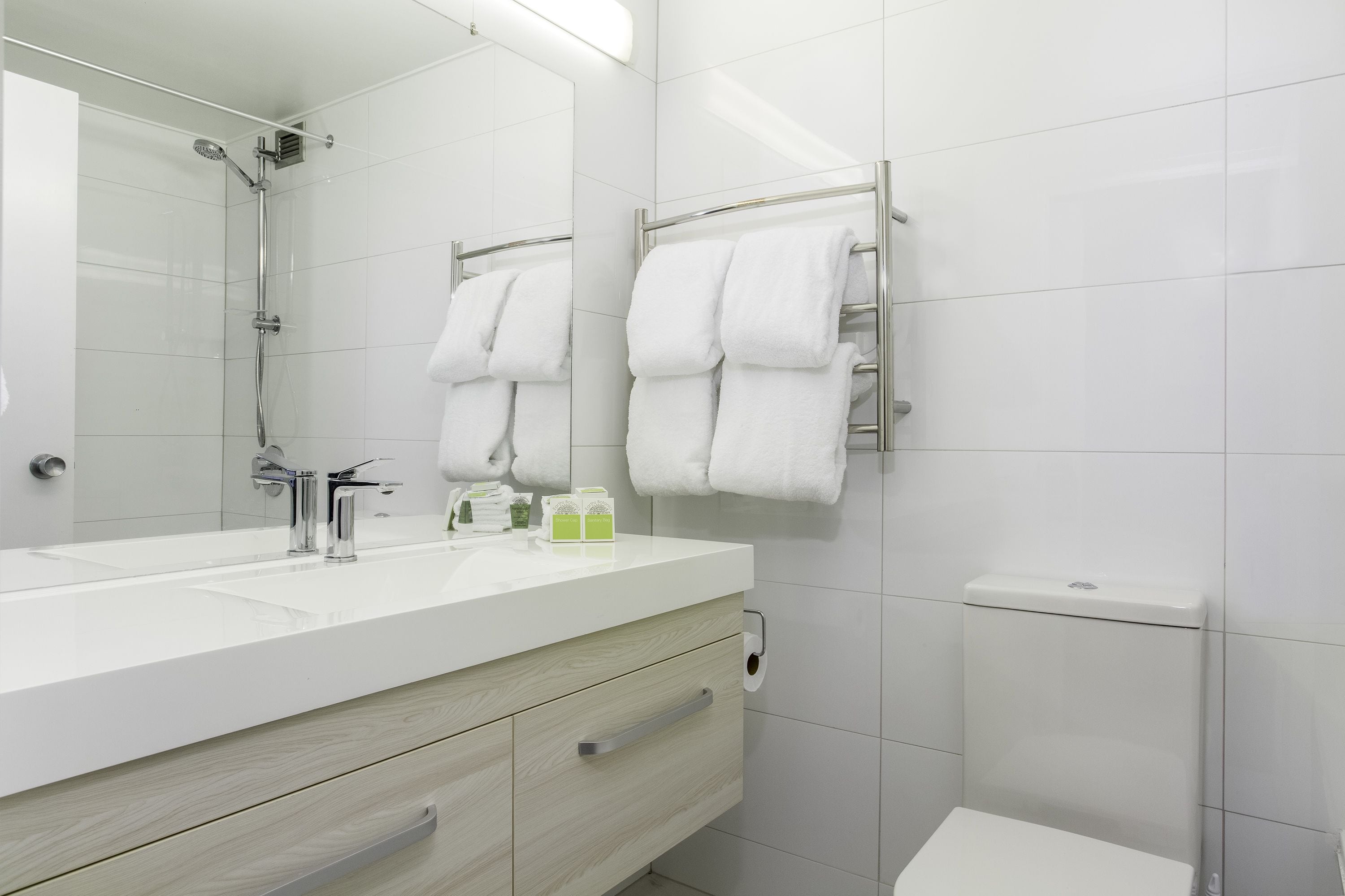 A modern bathroom with a white sink, mirror, and towel rack.