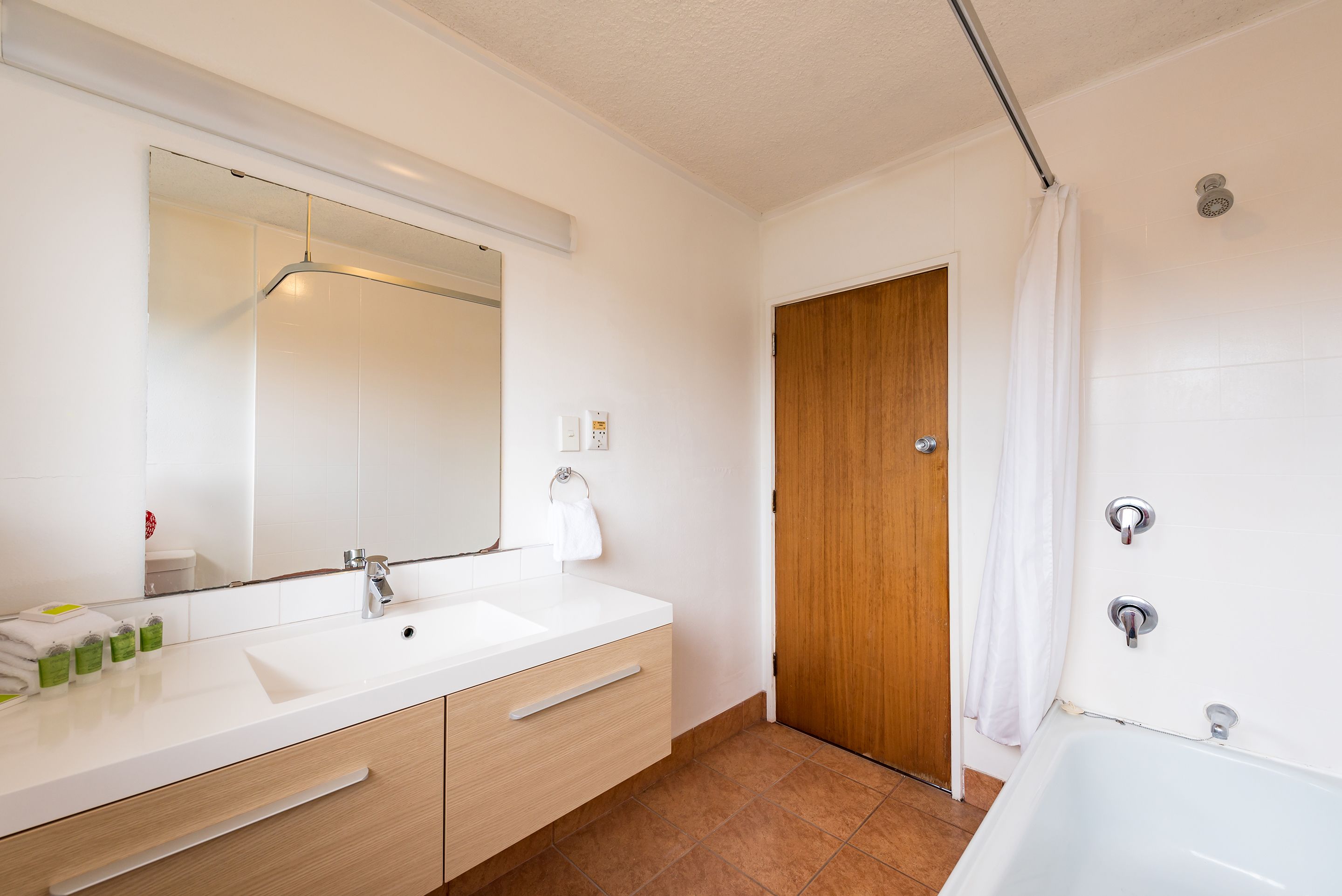 A modern bathroom with a white sink, mirror, and shower.