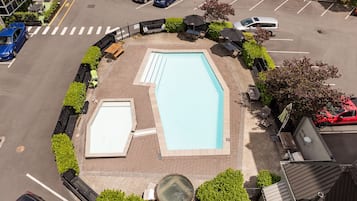 An aerial view of a swimming pool surrounded by a landscaped area with seating and umbrellas.