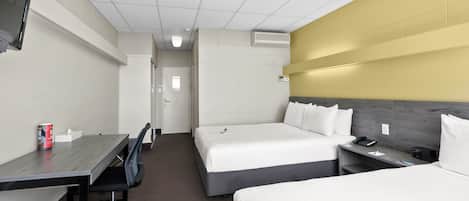 Une chambre d’hôtel avec deux lits, un bureau, une chaise, une télévision et une table de chevet avec un téléphone.