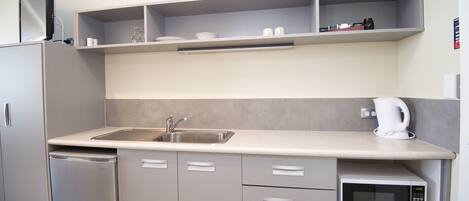 A modern kitchen with a built-in microwave, a sink, and a coffee maker.
