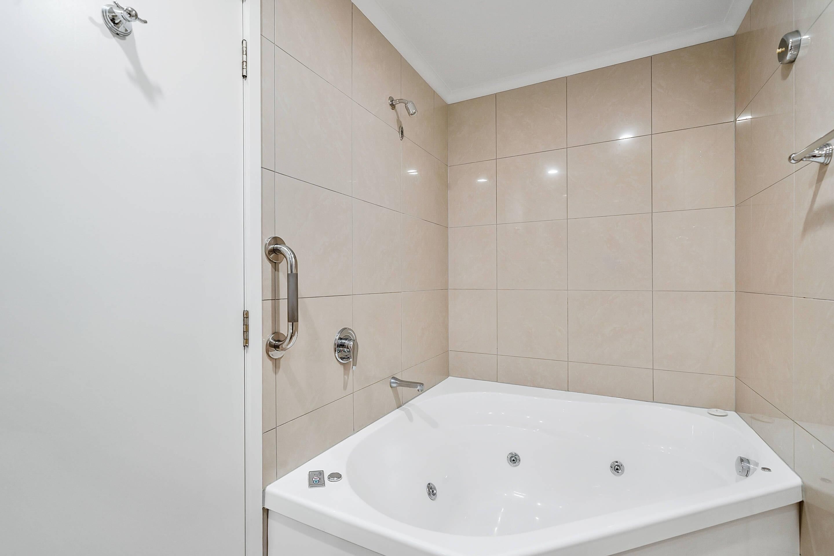 A modern bathroom with a large bathtub, a showerhead, and a toilet.